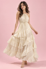 Vestido largo beige con cuello halter, espalda descubierta y volantes